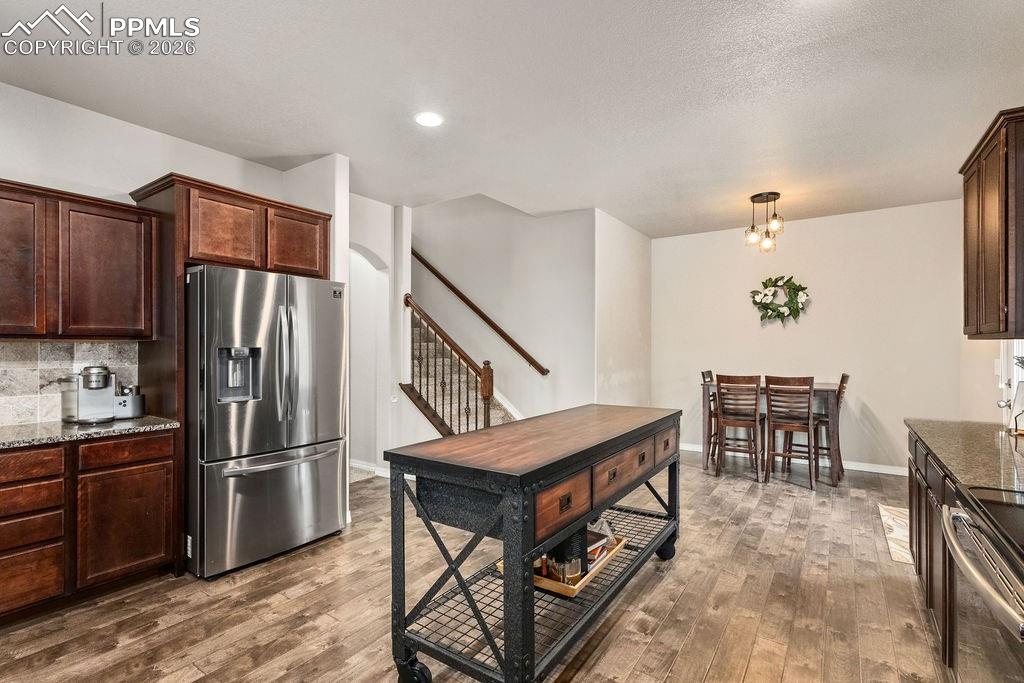 Image 14 of 43: Kitchen featuring dark wood finish cabinetry, dark stone counters, stainles