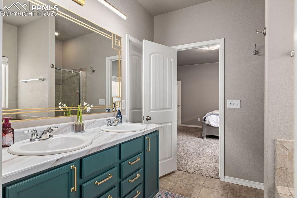 Image 17 of 43: Main floor primary bathroom with double vanity, a stall shower, ensuite bat