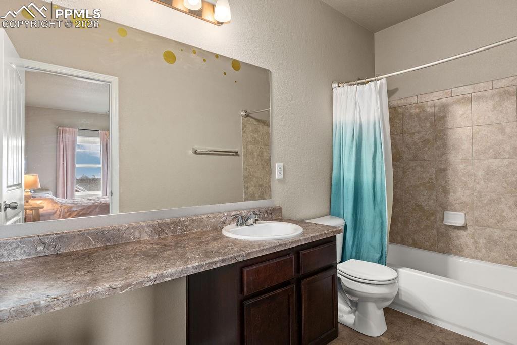 Image 32 of 43: Ensuite bathroom with vanity, shower / tub combo with curtain, tile pattern