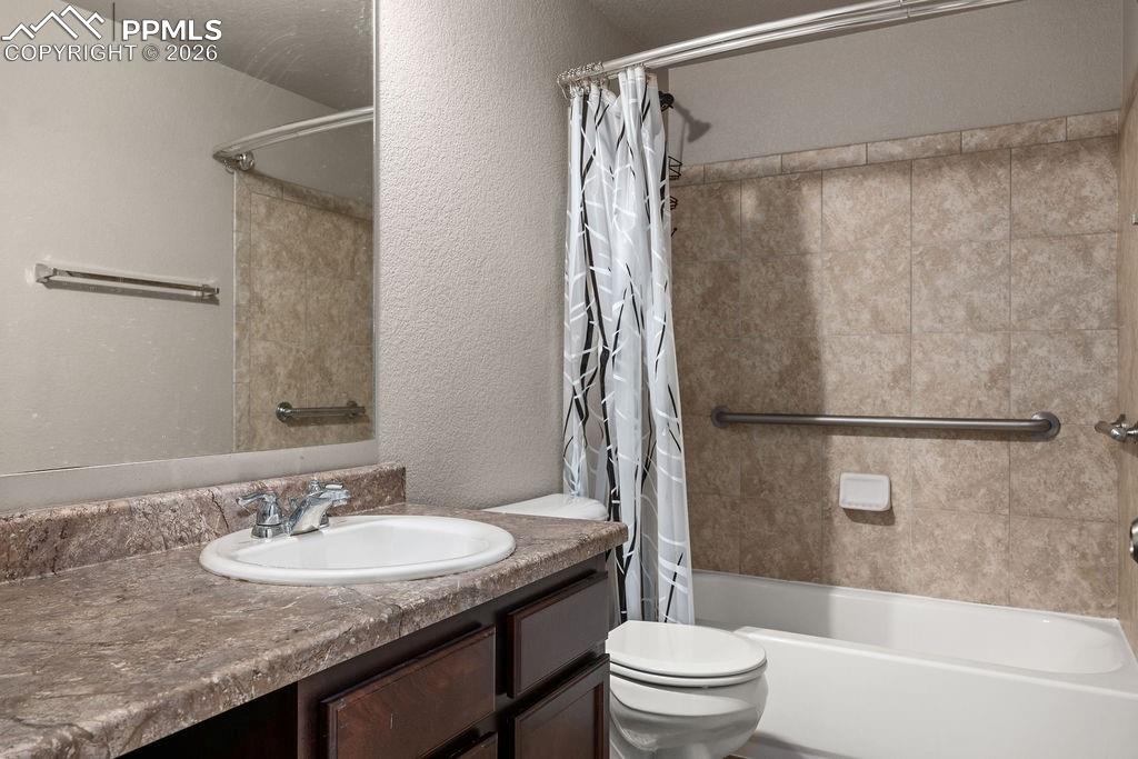 Image 41 of 43: Basement full bath with vanity, a textured wall, and shower / tub combo wit
