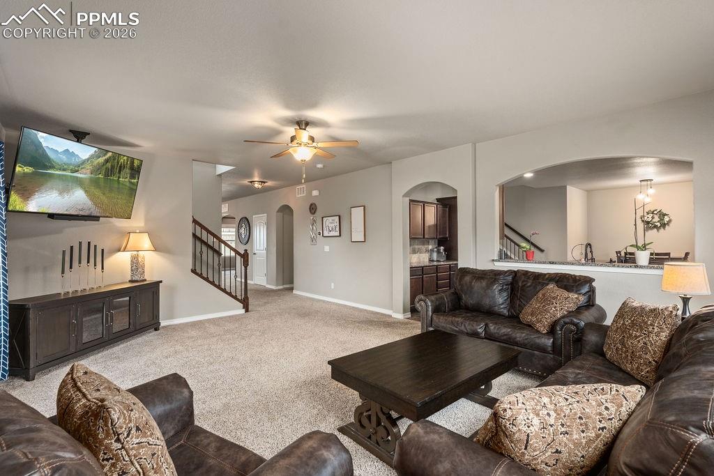 Image 9 of 43: Carpeted living room featuring arched walkways and a ceiling fan