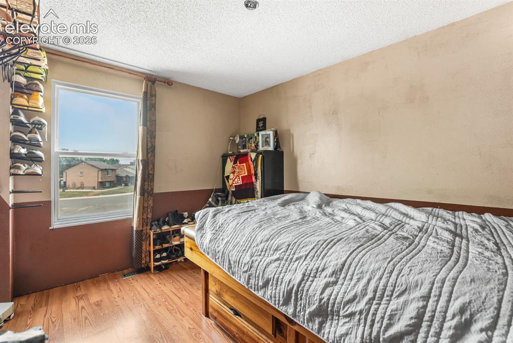 Image 13 of 33: Bedroom with wood-finish flooring, two-tone wall treatment, and a window wi