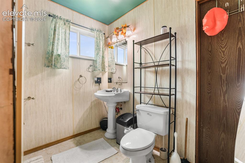 Image 17 of 33: Bathroom featuring a pedestal sink, a toilet, and a window with natural lig