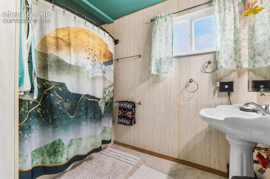 Image 18 of 33: Bathroom featuring a pedestal sink with chrome faucet, a window with light-