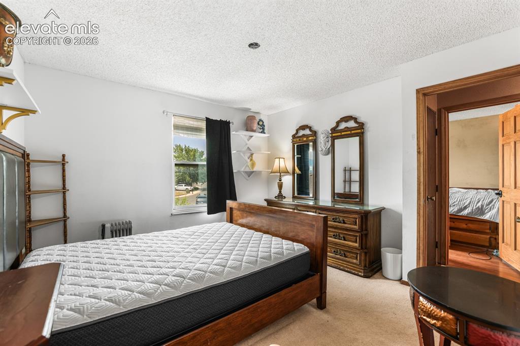 Image 22 of 33: Carpeted bedroom with textured ceiling and neutral wall paint