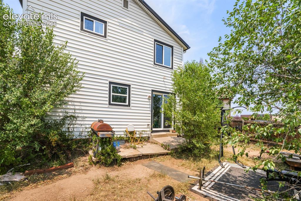 Image 31 of 33: White horizontal siding exterior with black trim windows, a concrete patio,
