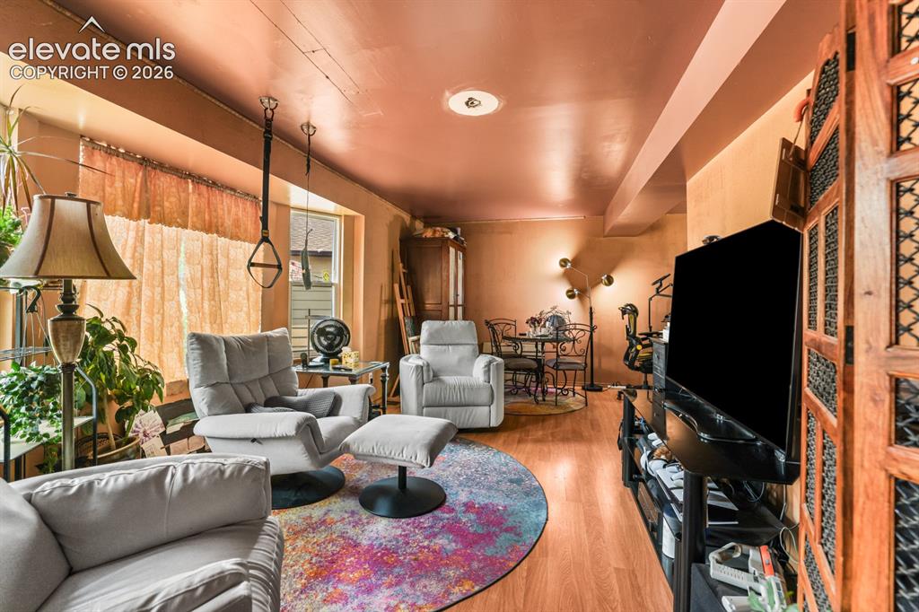 Image 7 of 33: Expansive living area featuring warm-toned walls, wood-finish flooring, and