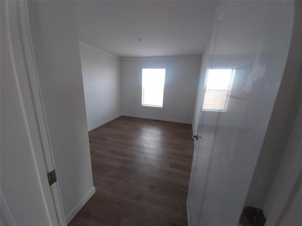 Image 15 of 28: Spare room featuring dark wood-style floors and crown molding