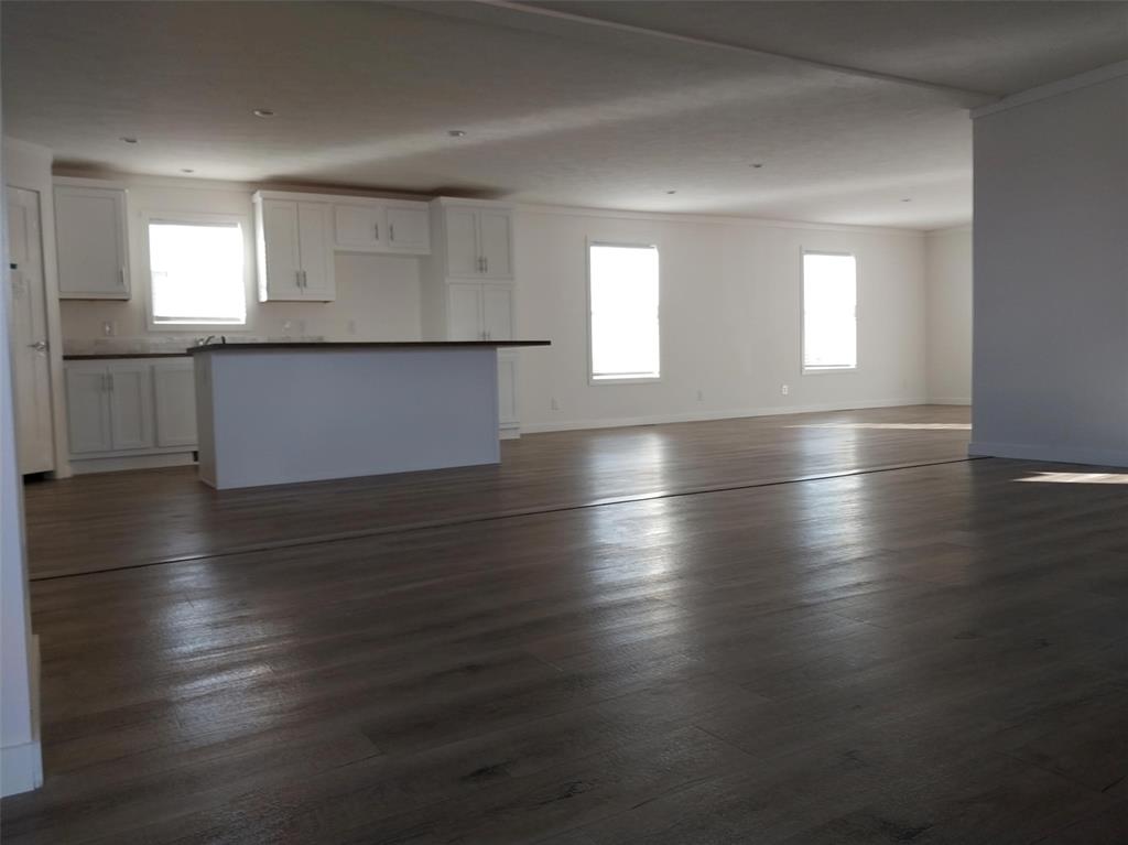 Image 23 of 28: Unfurnished living room with dark wood finished floors and crown molding