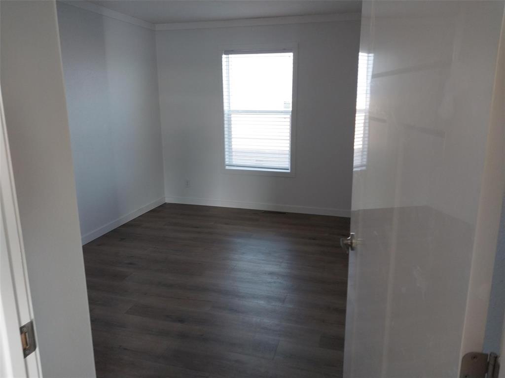 Image 25 of 28: Empty room featuring ornamental molding and dark wood-style floors