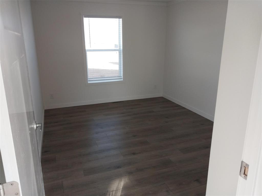 Image 26 of 28: Unfurnished room with dark wood-type flooring and baseboards