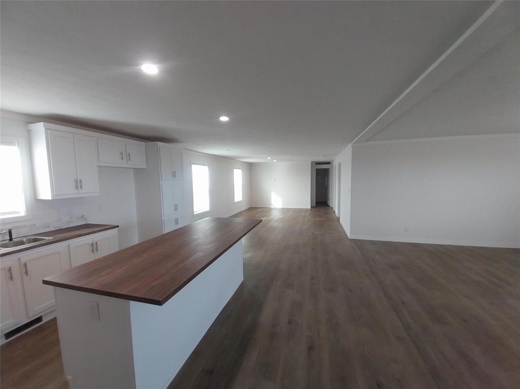 Image 7 of 28: Kitchen with white cabinets, dark wood-style flooring, a center island, ope