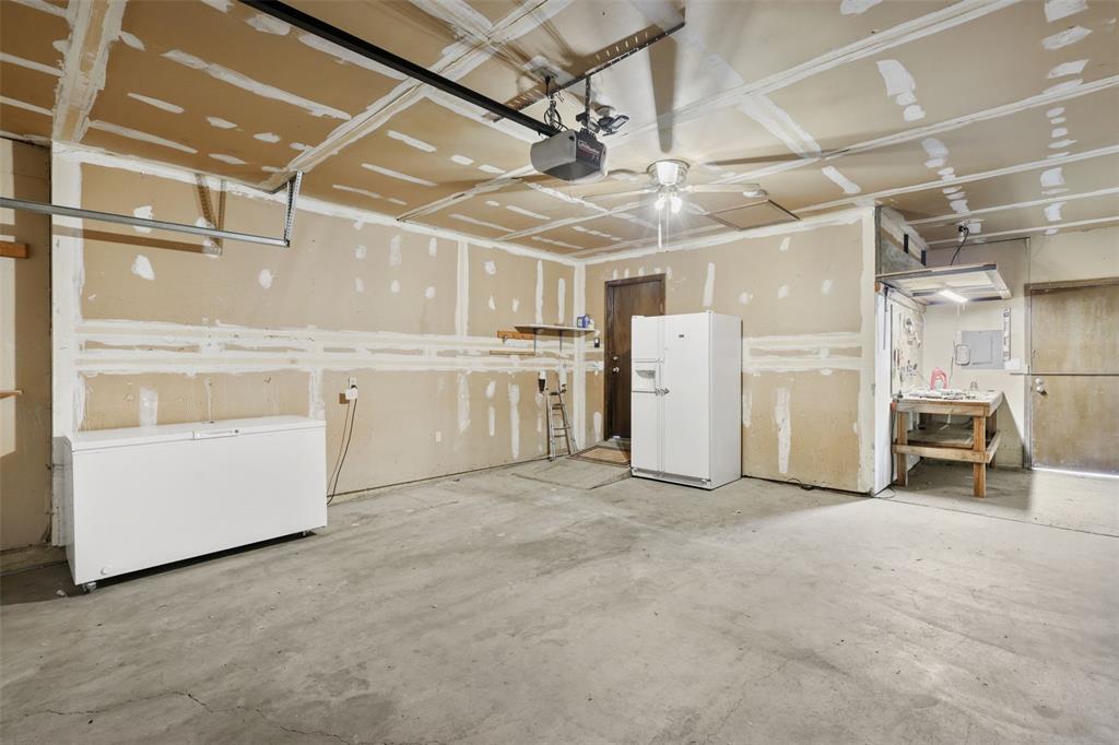 Image 26 of 32: Garage with 2nd refrigerator, newer chest freezer and workbench