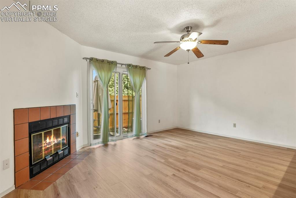 Image 2 of 30: Unfurnished living room featuring wood finished floors, a ceiling fan, a te