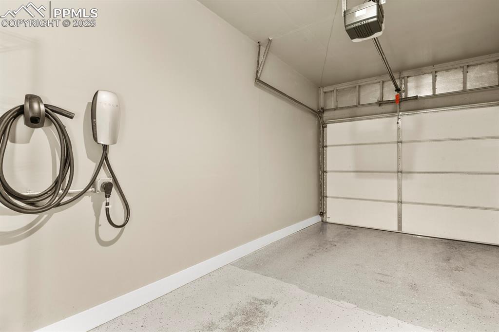 Image 27 of 30: Garage with a garage door opener and electric car charger
