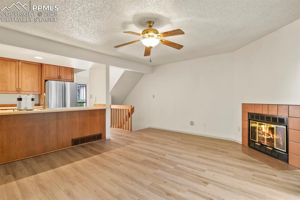 Image 4 of 30: Unfurnished living room with light wood-type flooring, a ceiling fan, a til