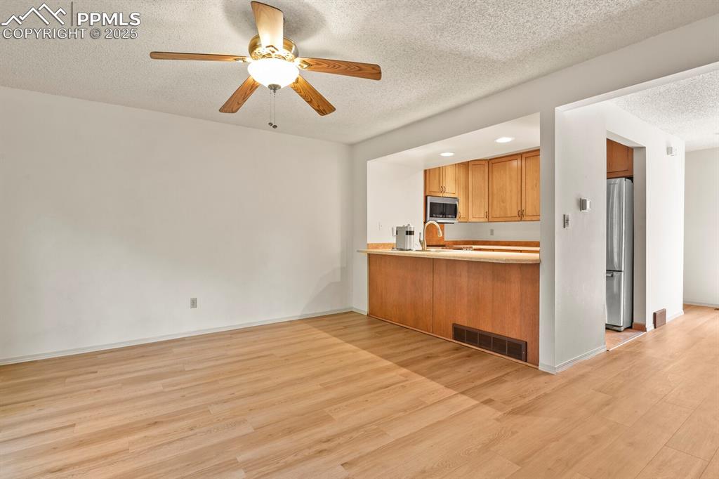 Image 5 of 30: Kitchen featuring light wood-style floors, a textured ceiling, ceiling fan,