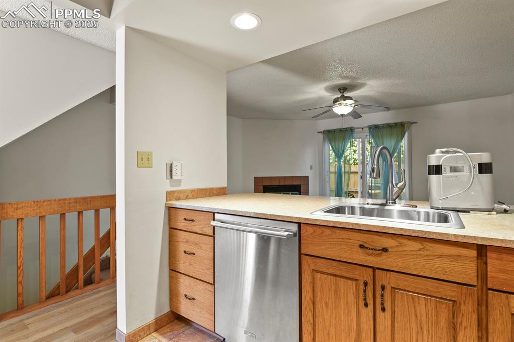 Image 9 of 30: Kitchen featuring stainless steel dishwasher, ceiling fan, brown cabinetry,