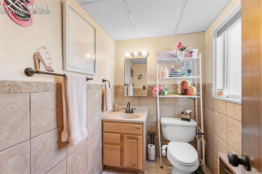 Image 8 of 22: Bathroom featuring vanity, light tile patterned floors, tile walls, and wai