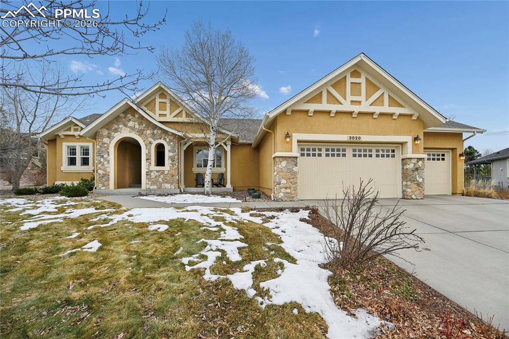 Caption: View of front facade featuring stone siding, stucco siding, driveway, an attached garage, and a porc
