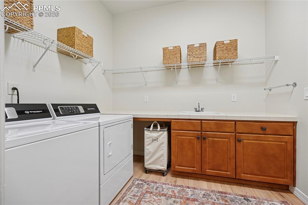 Image 11 of 50: Laundry room featuring separate washer and dryer, light wood finished floor