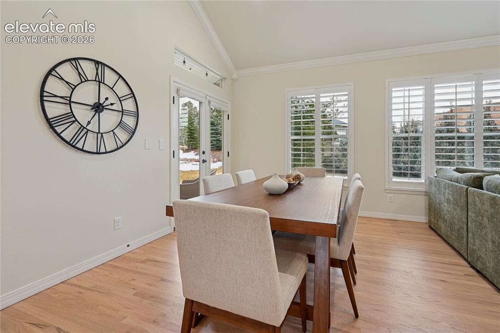 Image 12 of 49: Dining area with vaulted ceiling, french doors, light wood finished floors,