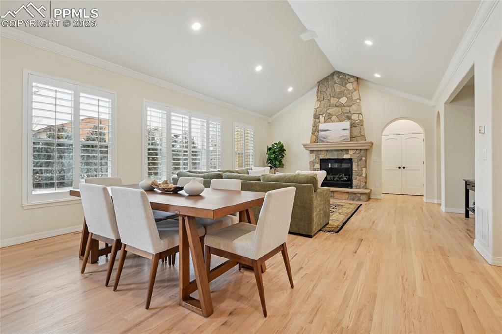 Image 13 of 50: Dining space with light wood-style flooring, a stone fireplace, crown moldi