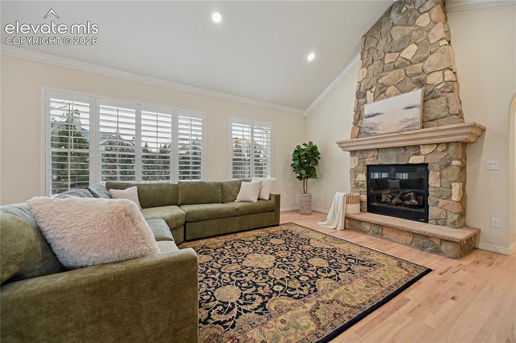 Image 15 of 49: Living room featuring vaulted ceiling, a fireplace, light wood-style floori