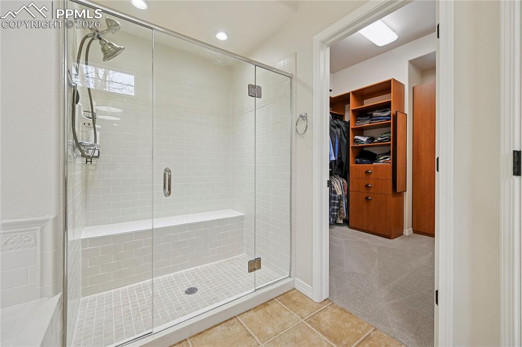 Image 20 of 50: Full bathroom featuring a walk in closet, a shower stall, light tile patter