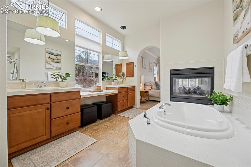 Image 21 of 50: Bathroom featuring a bath, vanity, light tile patterned flooring, a high ce