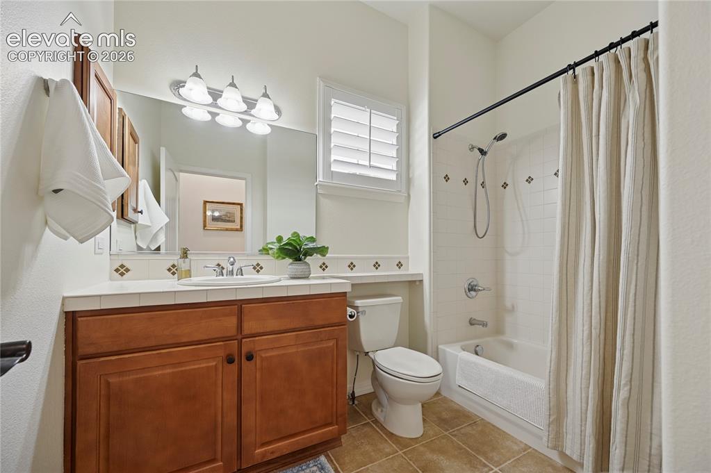 Image 27 of 49: Bathroom featuring shower / bath combo with shower curtain, vanity, and lig