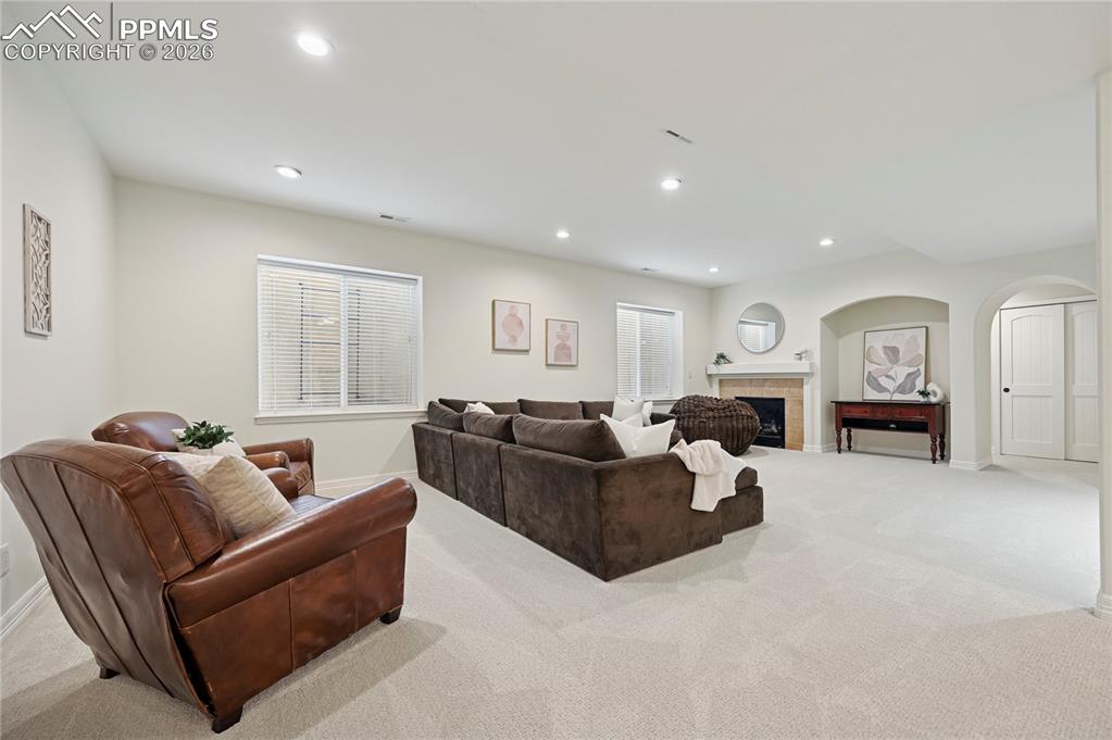 Image 32 of 50: Carpeted living area featuring a fireplace, recessed lighting, and arched w