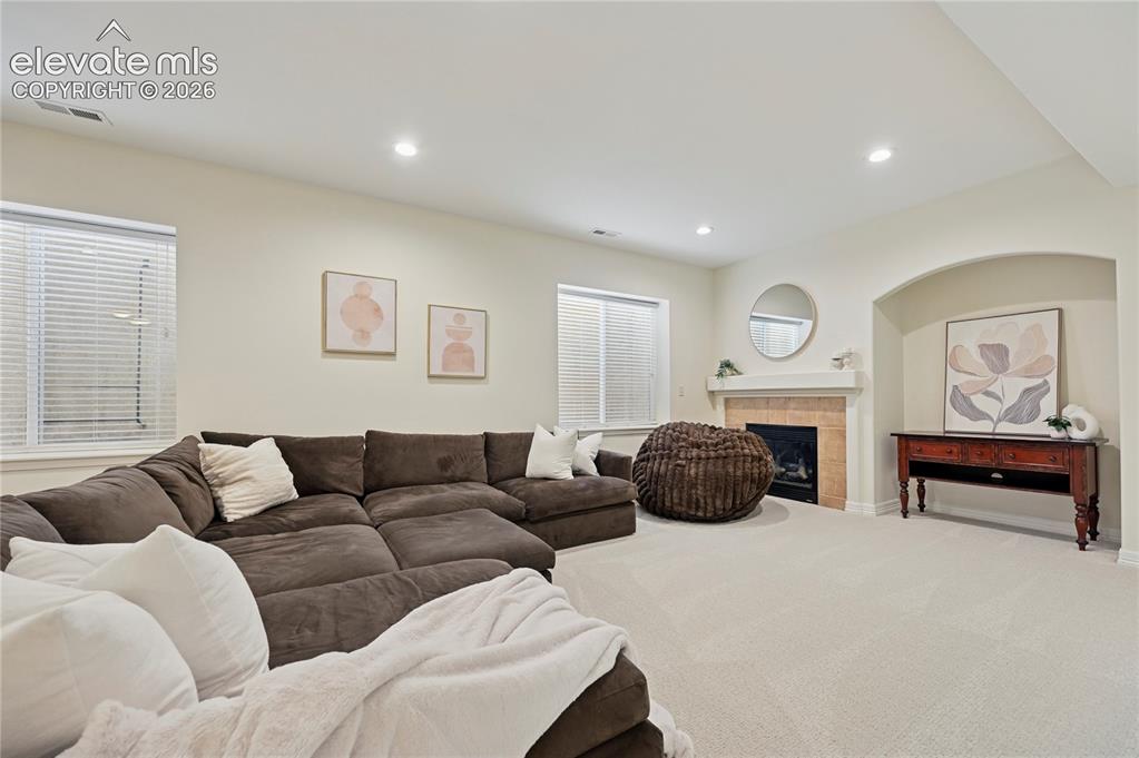 Image 33 of 49: Living room featuring a tile fireplace, carpet floors, and recessed lightin