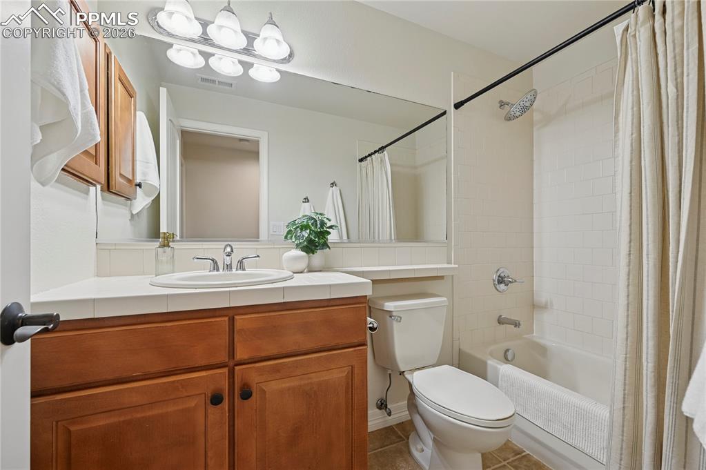Image 36 of 49: Bathroom featuring shower / bath combination with curtain, vanity, and tile