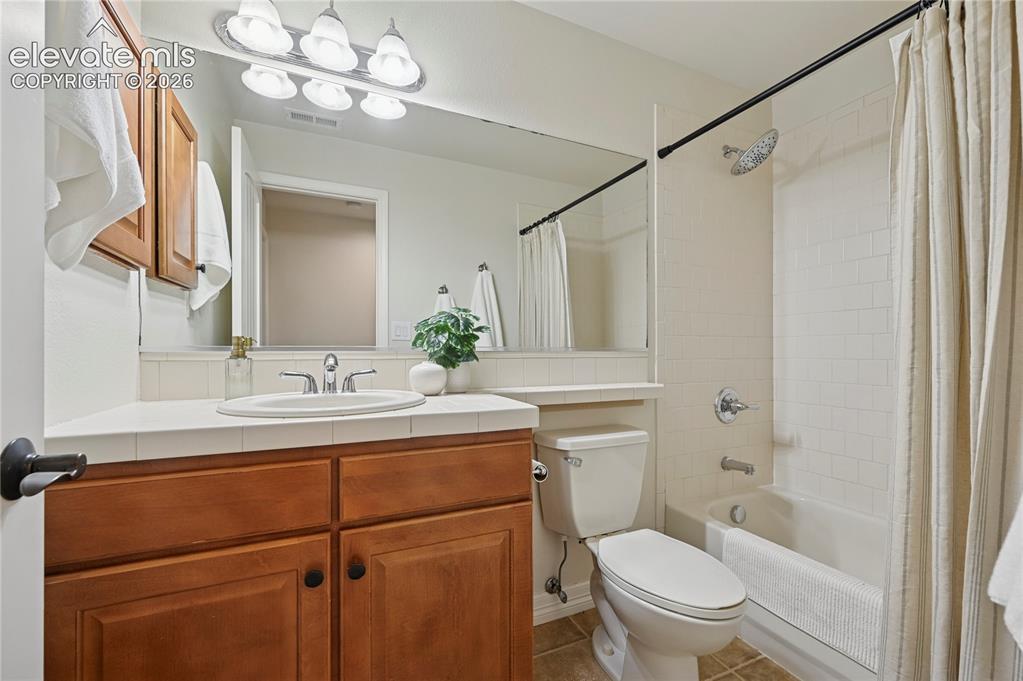 Image 36 of 49: Bathroom featuring shower / bath combination with curtain, vanity, and tile
