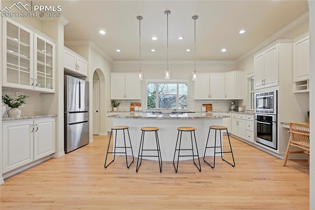 Image 7 of 50: Kitchen featuring decorative light fixtures, a breakfast bar, white cabinet