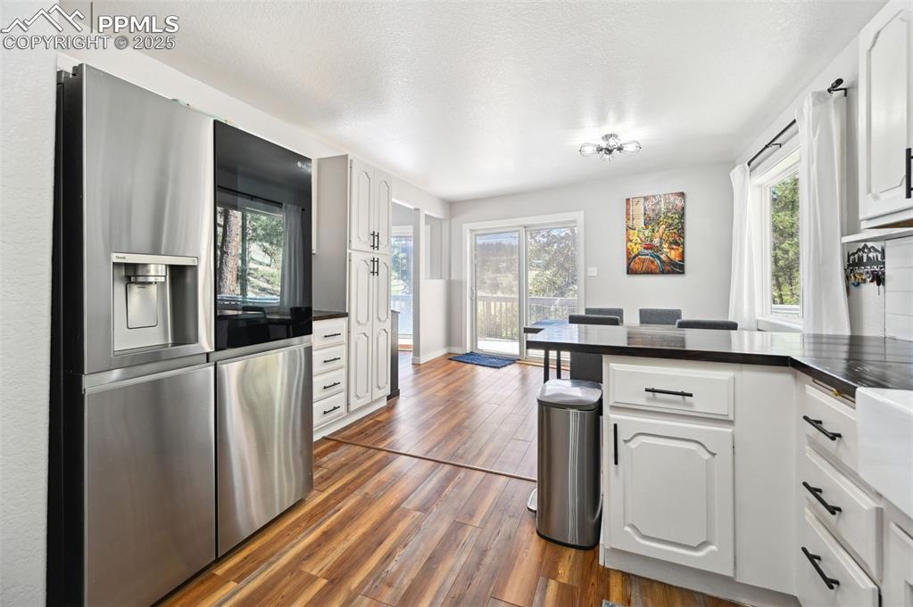 Image 10 of 49: Kitchen with dark countertops, dark wood finished floors, a peninsula, stai