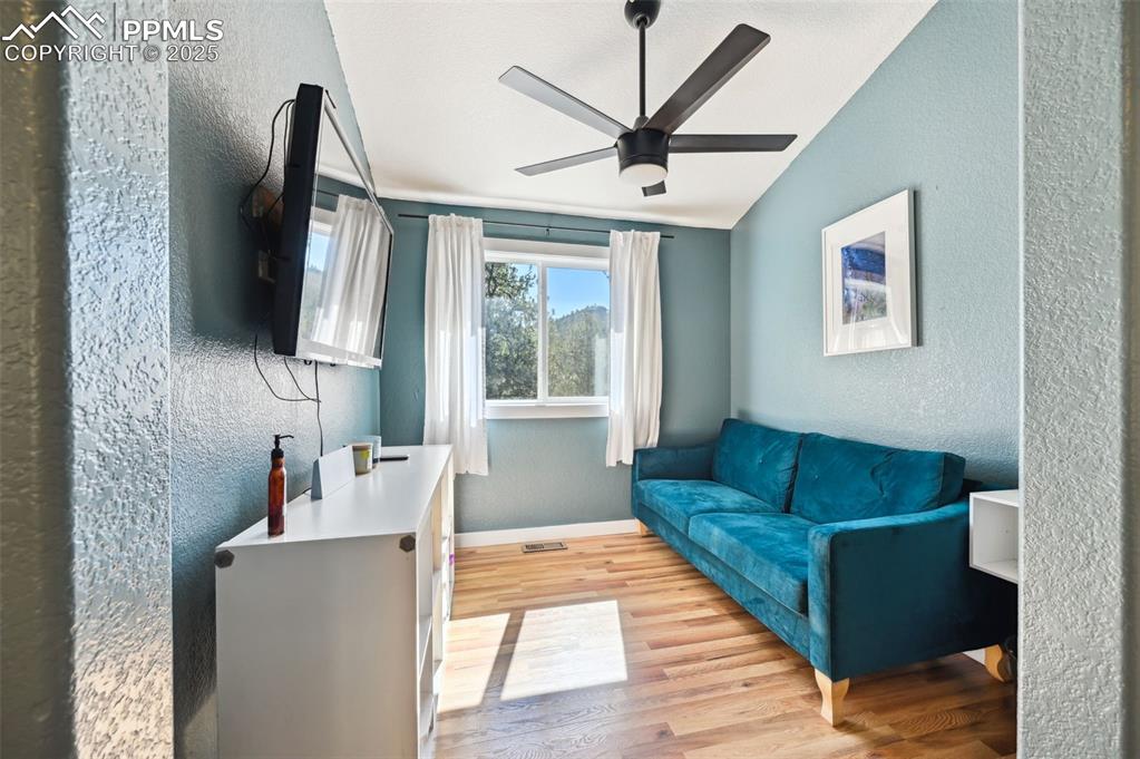 Image 16 of 49: Living area featuring a textured wall, light wood-style floors, a ceiling f