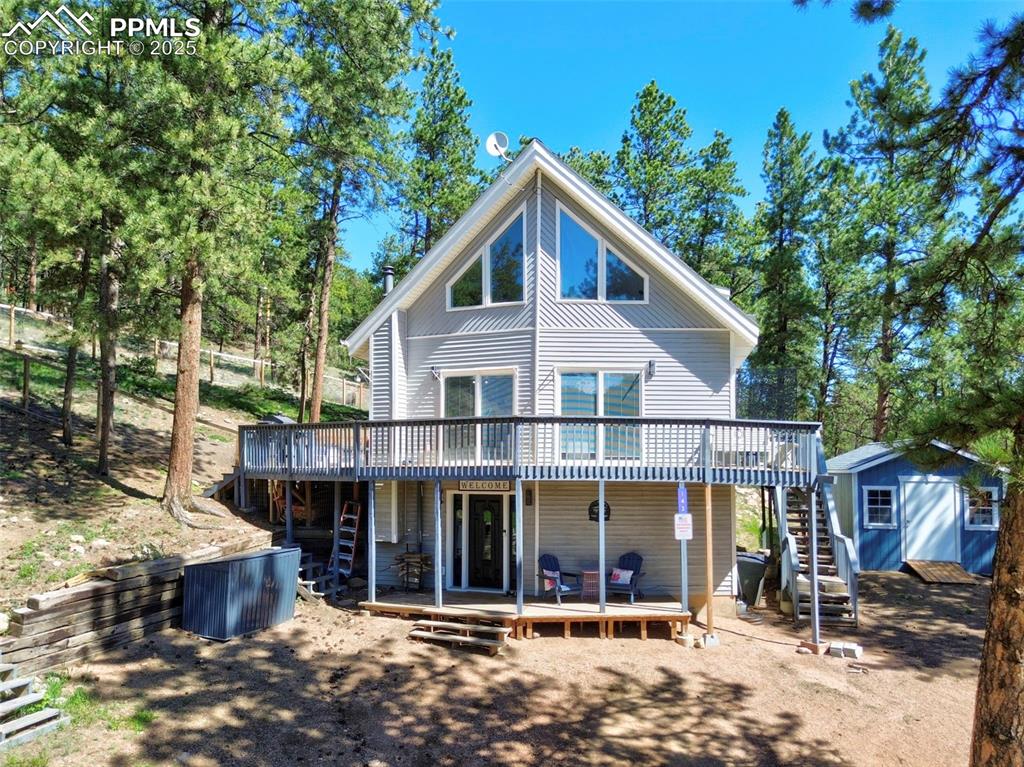 Image 2 of 49: Rear view of property with stairs, a deck, and a shed