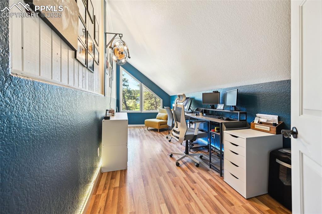 Image 21 of 49: Home office featuring a textured wall, light wood-type flooring, and lofted