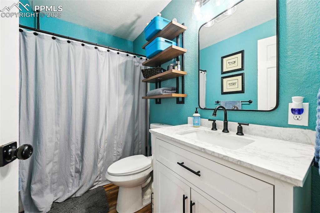 Image 23 of 49: Full bath with vanity, wood finished floors, a shower with curtain, and a t