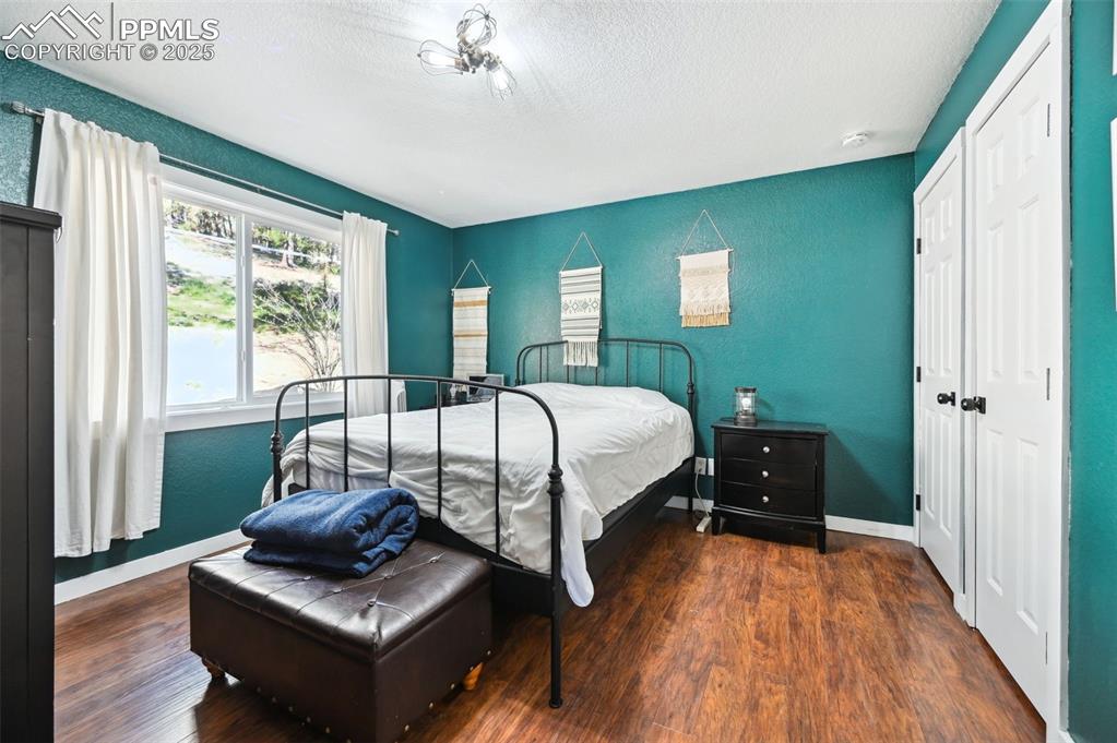Image 24 of 49: Bedroom featuring wood finished floors, a textured ceiling, a textured wall