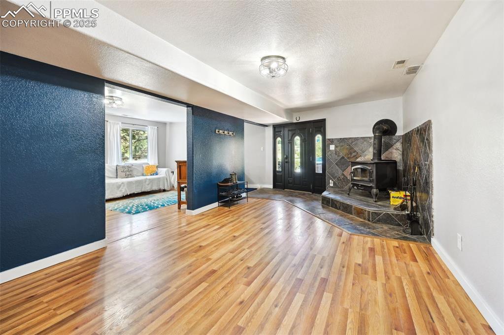 Image 32 of 49: Unfurnished living room featuring a wood stove, wood finished floors, and a