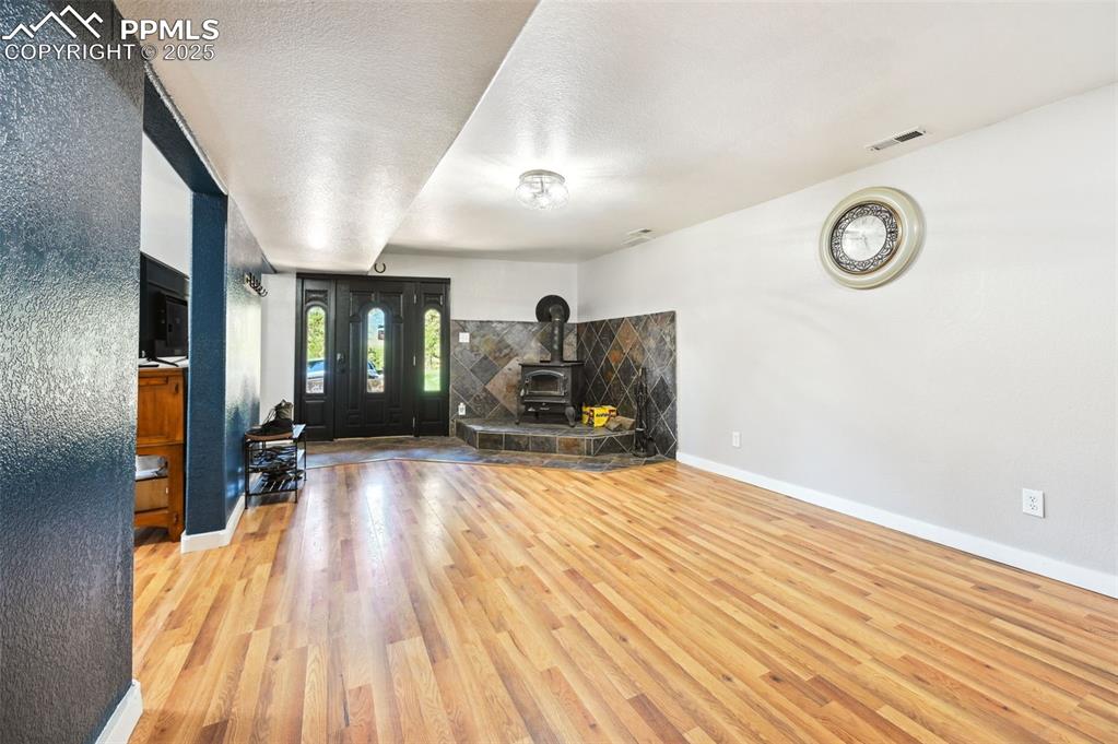 Image 33 of 49: Unfurnished living room with wood finished floors and a wood stove