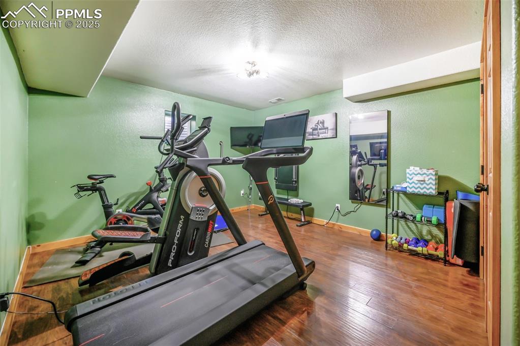 Image 34 of 49: Exercise area featuring wood finished floors and a textured ceiling