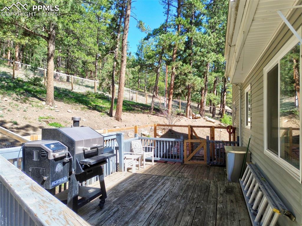 Image 38 of 49: Wooden terrace with a fenced backyard and view of wooded area
