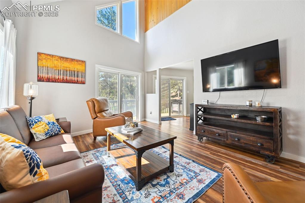 Image 4 of 49: Living room with a high ceiling and wood finished floors