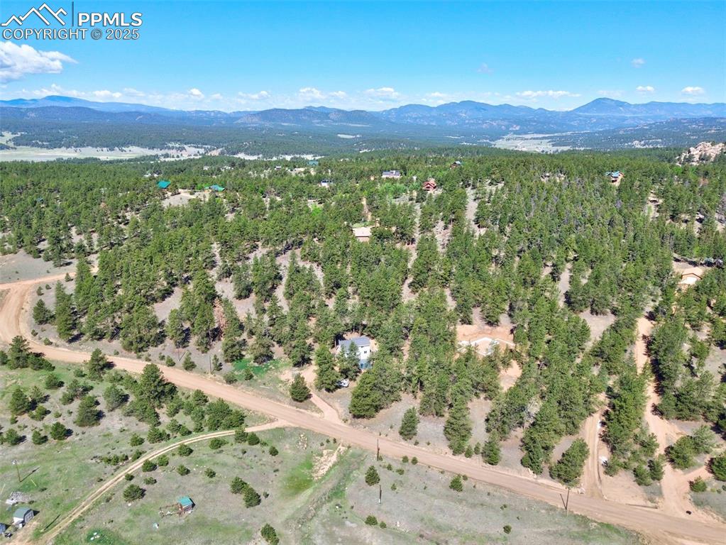 Image 44 of 49: Aerial view of property and surrounding area with mountains and a forest