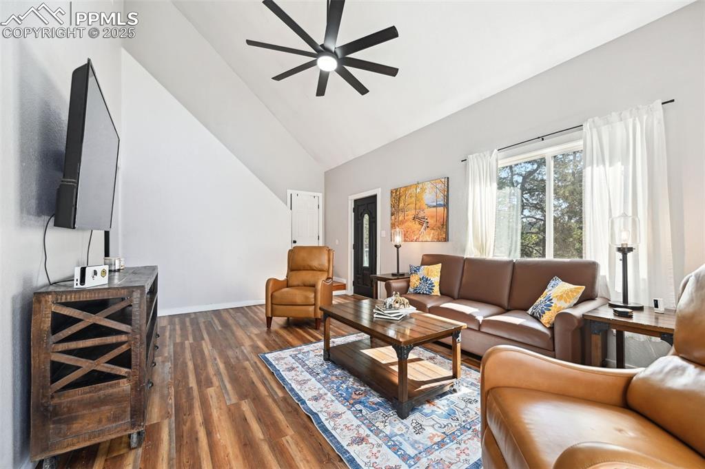 Image 5 of 49: Living room with a ceiling fan, dark wood-style flooring, and high vaulted 