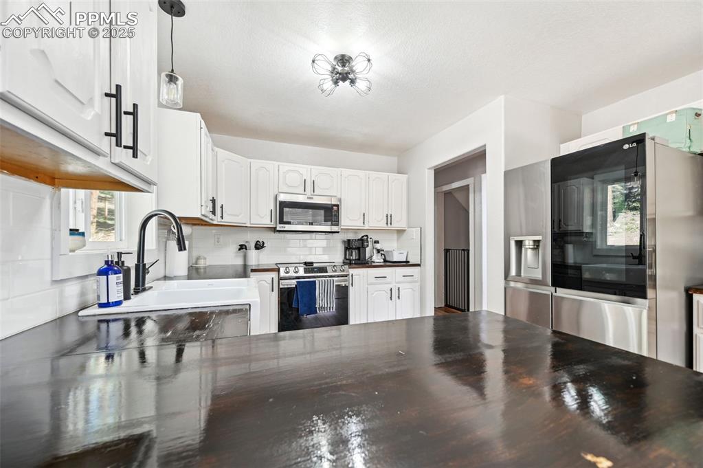 Image 7 of 49: Kitchen with stainless steel appliances, tasteful backsplash, dark countert
